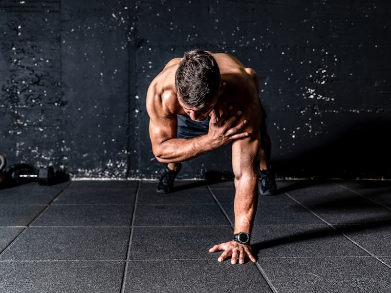 Young sweaty strong and fit muscular man push ups workout with touching his shoulder on one hand in ...