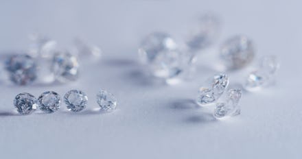 Macro close up of experienced goldsmith sorting high quality diamonds, selecting them to make precio...