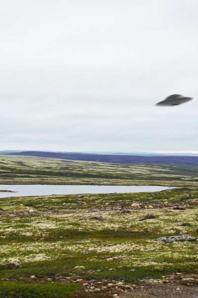 Flying saucer UFO over tundra in the Kola Peninsula in Russia. UFO floating above tundra landscape n...