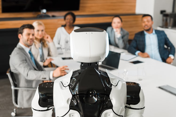 selective focus of multicultural businesspeople looking at robot in conference hall