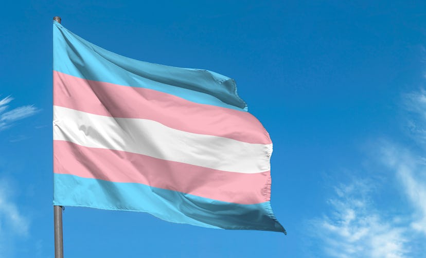 Transgender flag waving against blue sky, transgender pride flag in a street