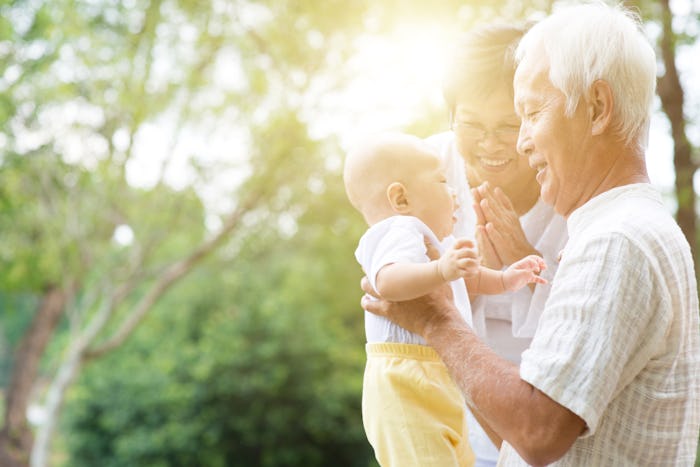 Grandparents holding baby grand baby at outdoor park