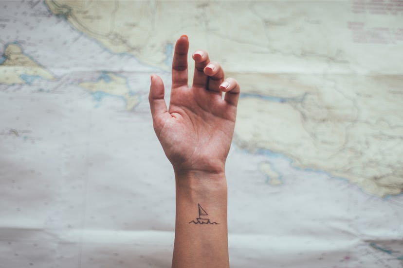 Small sailboat tattoo on female ankle. Travel, tourist concept