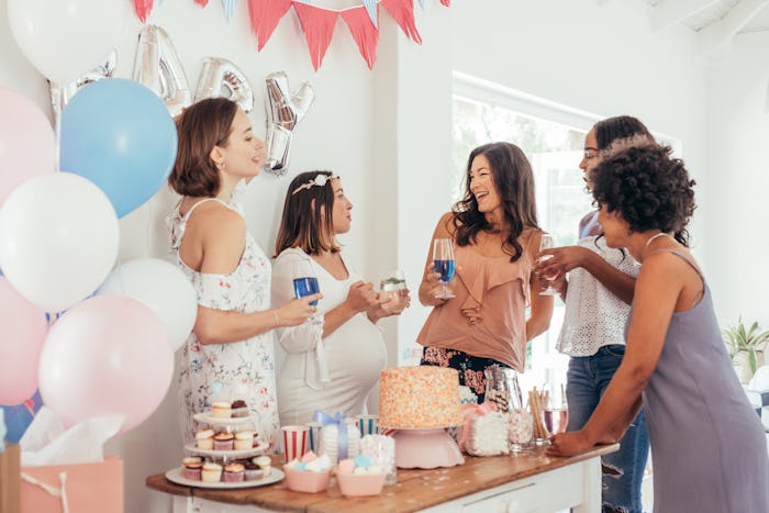 Pregnant woman celebrating baby shower party with female friends at home. Group of multi-ethnic wome...