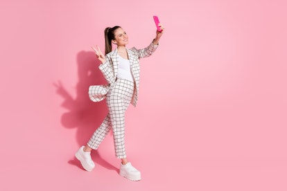 Photo portrait full body view of woman taking selfies on the go showing v-sign isolated on pastel pi...