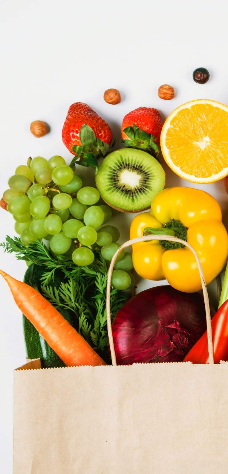 Fruits and vegetables on a light background in a Kraft bag from the store. Healthy and healthy food ...