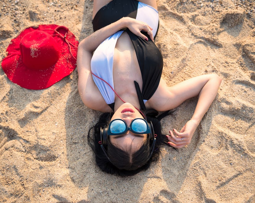 Close-up woman listening to music with headphones on the beach. Lady relax during summer vacation.Se...