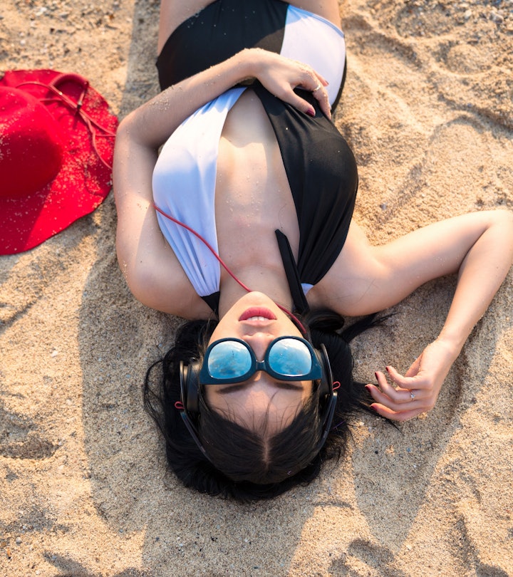 Close-up woman listening to music with headphones on the beach. Lady relax during summer vacation.Se...