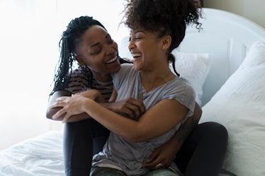 Lesbian couple relaxing on bed, hugging, laughing
