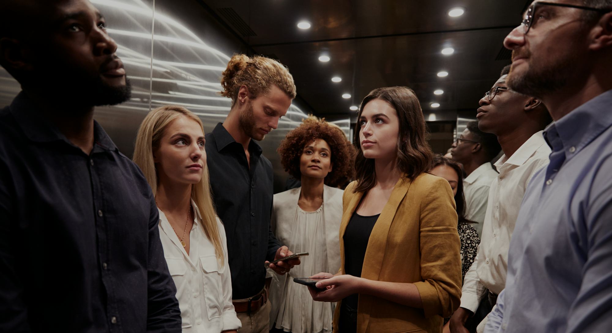 Work colleagues stand waiting together in an elevator at their office