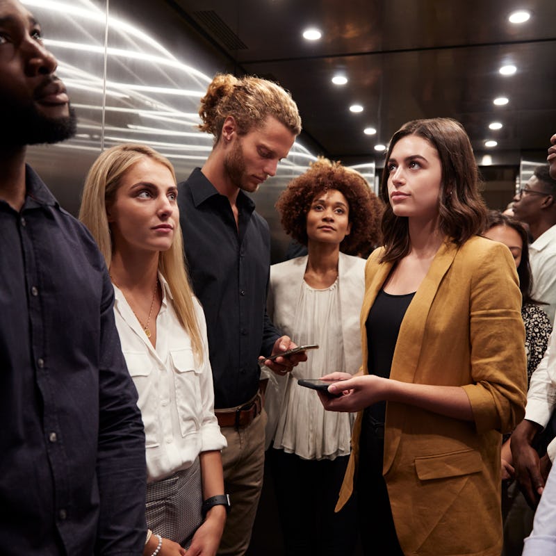 Work colleagues stand waiting together in an elevator at their office