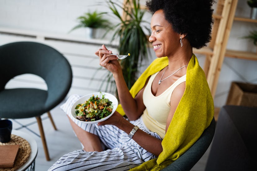 A curly woman eating a salad made of ingredients for sun protection 