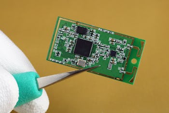 IT industry engineer holds with tweezers mini wireless bluetooth module for mobile devices. Mass pr...