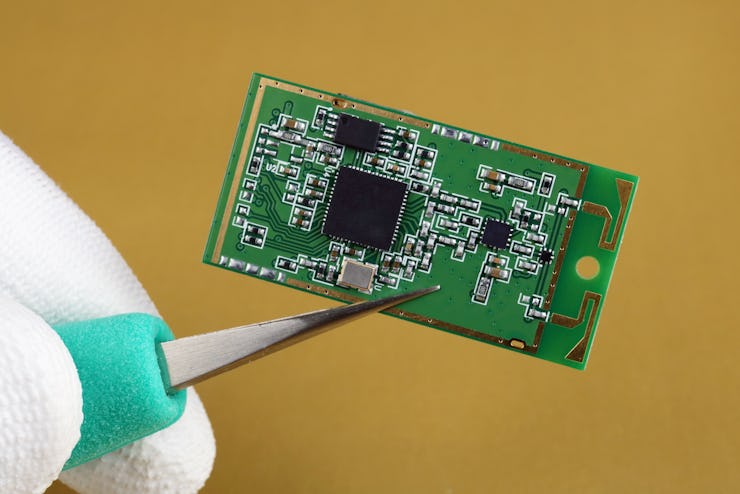 IT industry engineer holds with tweezers mini wireless bluetooth module for mobile devices. Mass pr...