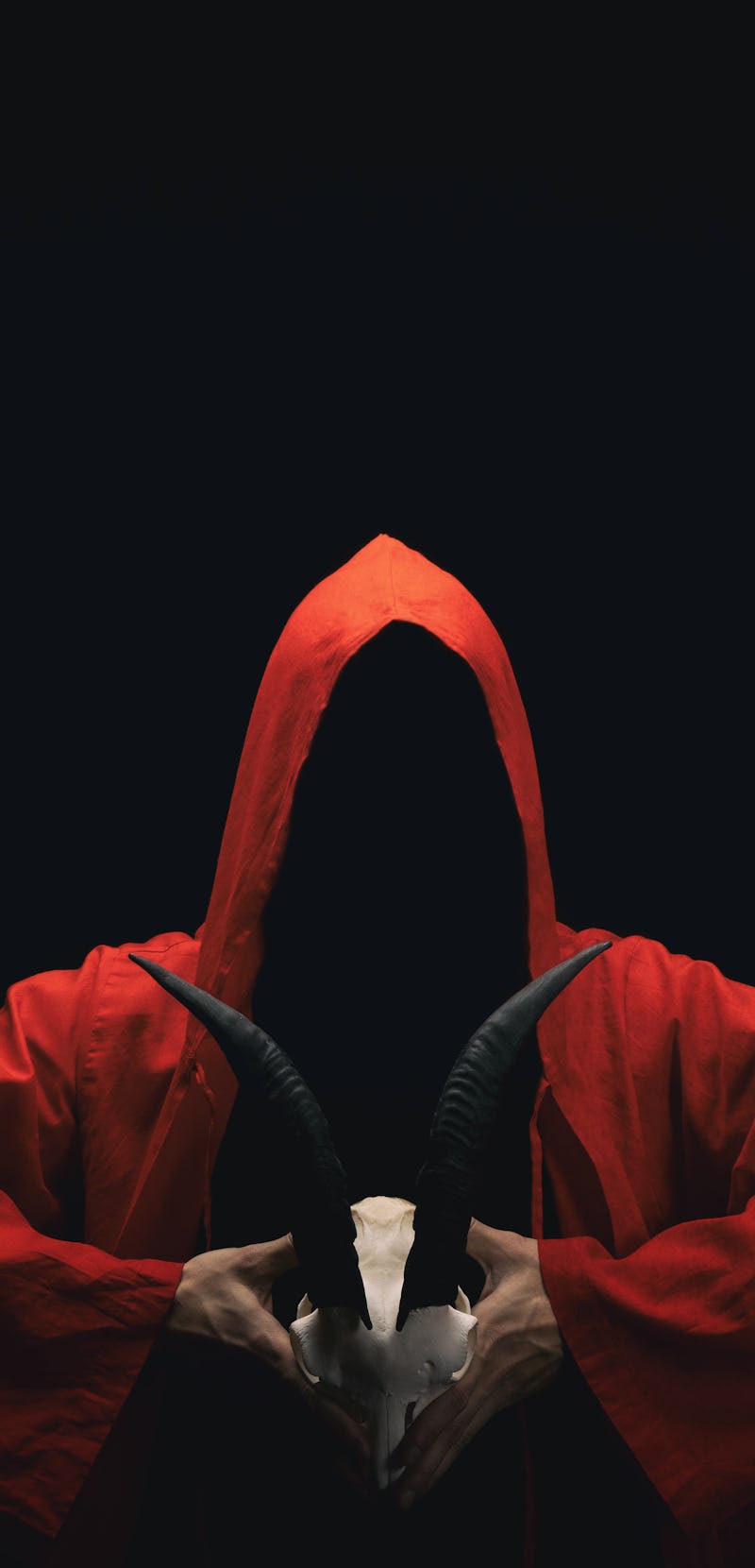 Mystery people in a red hooded cloaks in the dark. Hiding face in shadow. Pointing up with fingers. ...