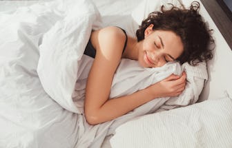 Woman sleeping. High angle view of beautiful young woman lying in bed and keeping eyes closed while ...