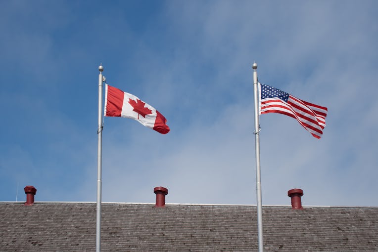 The flags of Canada and the US fly on a flag pole
