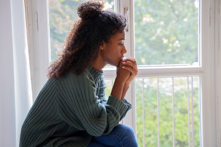 Young worried woman looking out of the window