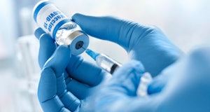 Male doctor hand wears medical glove holding syringe taking covid 19 corona virus liquid vaccine fro...