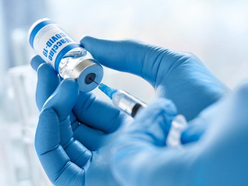 Male doctor hand wears medical glove holding syringe taking covid 19 corona virus liquid vaccine fro...