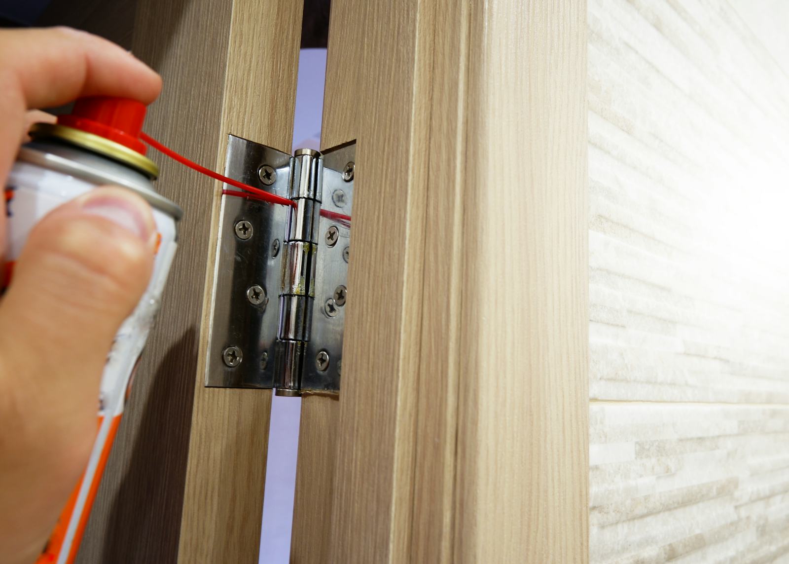 A man lubricates <b>door</b> hinges with oil. 