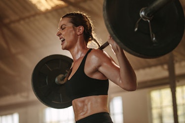 Female bodybuilder doing an exercise with a heavy weight bar