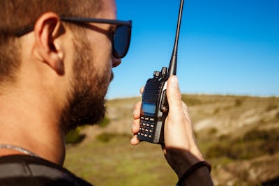 Young handsome man talking on walkie talkie radio, enjoying canyon view.