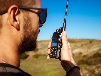 Young handsome man talking on walkie talkie radio, enjoying canyon view.