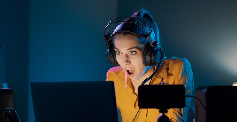 Shocked woman playing at night with her laptop, she loses the game and she is disappointed
