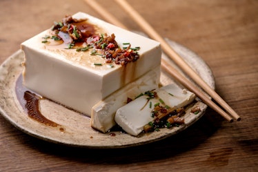 Silk tofu japanese soy cheese whole piece with chili, chive ginger and soy sauce topping on ceramic ...