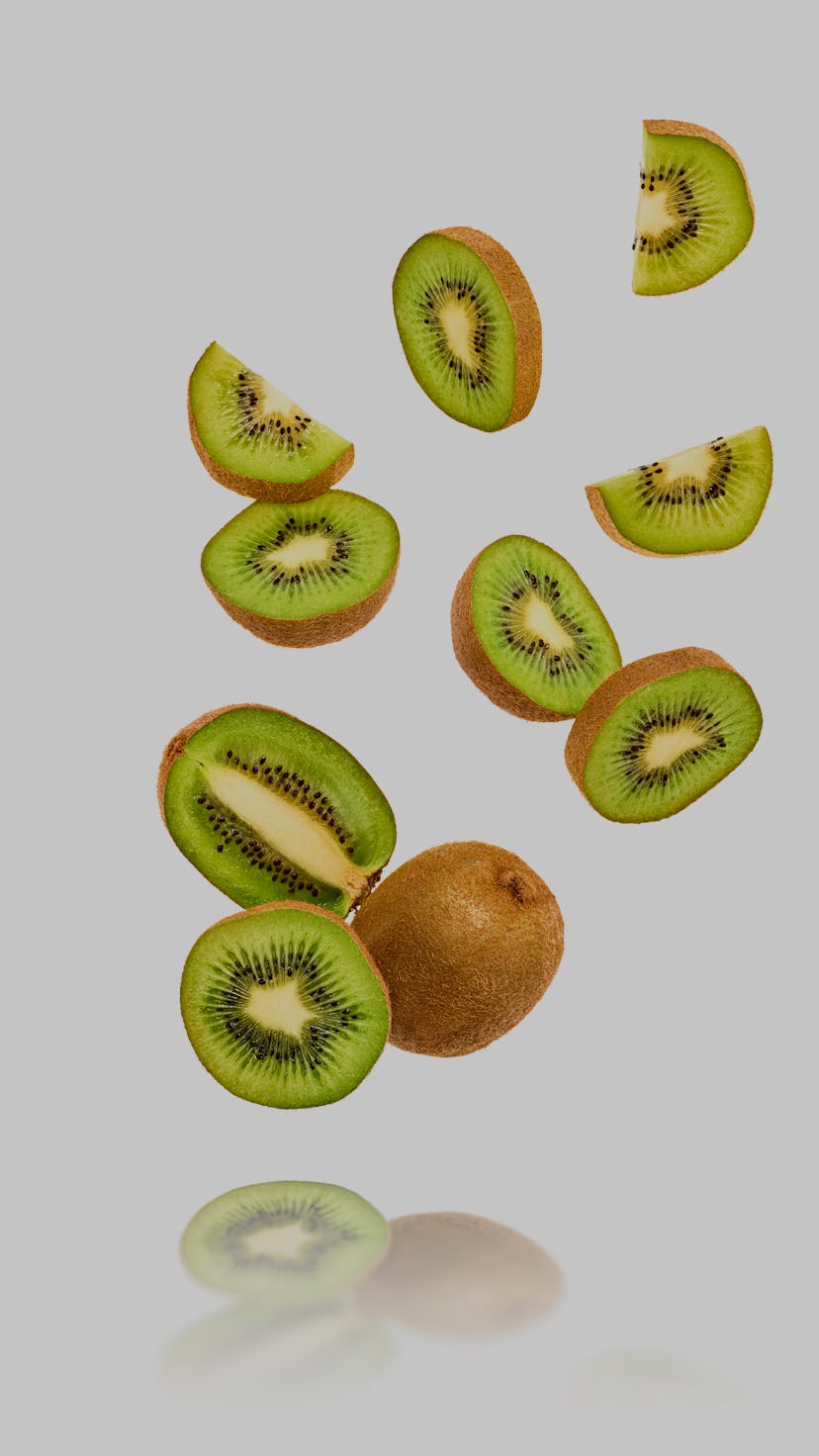 Fresh kiwi fruit flying in air on yellow. Fruity green color diet food. Summer whole, cut kiwi backg...