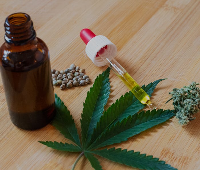Cannabis oil, seeds and flower placed around weed leaf