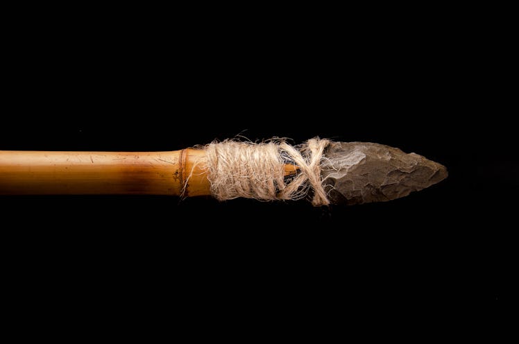 prehistoric javelin tied to a pole. Stone age. paleolithic. on black background
