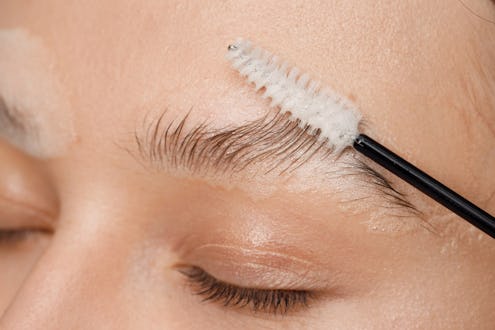 Master applies brow paste with a brush to eyebrows. Styling and lamination of eyebrows. Woman doing ...