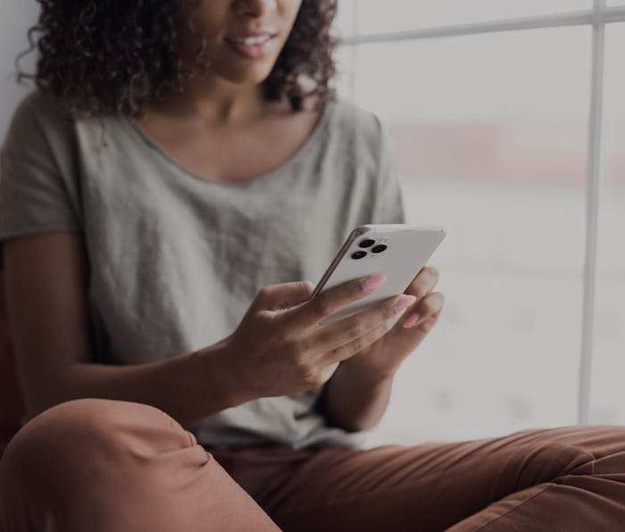 Young woman using smartphone at home. Student girl texting on mobile phone in her room. Communicatio...