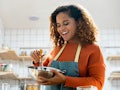 Young African American woman enjoying herself cooking in kitchen while staying at home