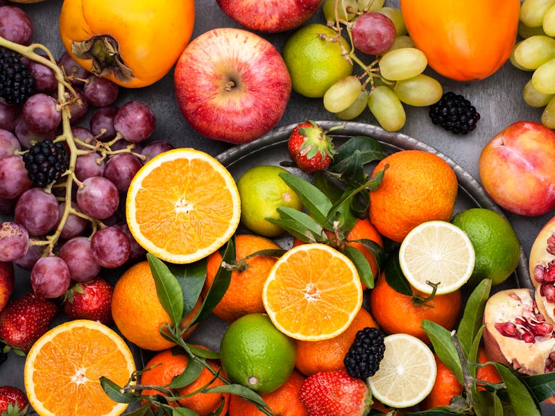 Assorted fruits. Different fruits on a gray background, the whole surface is covered with citrus fru...