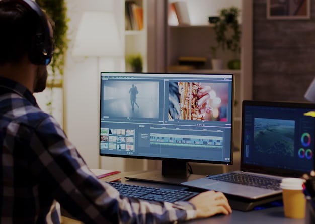 Film maker pointing at the monitor in home office while working on post production for a movie. Vide...