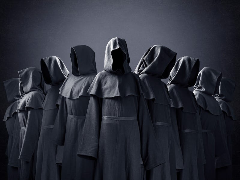 Group of nine scary figures in hooded cloaks in the dark