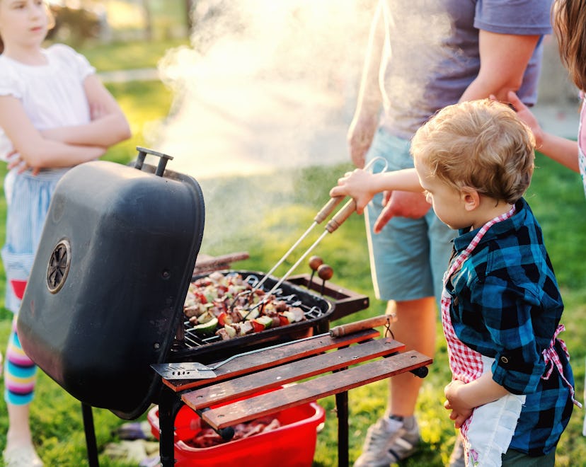 child grilling with father standing nearby for Labor Day
