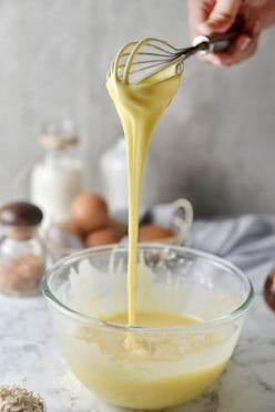 Making pancakes, cake, baking side view of baker hands pouring batter and whisking batter in bowl. C...
