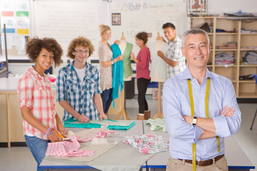 A medium shot of a teacher and young students smiling at camera in a home economics class.