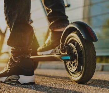 Close up of young man ready to discover the urban city at sunset with electric scooter or e-scooter