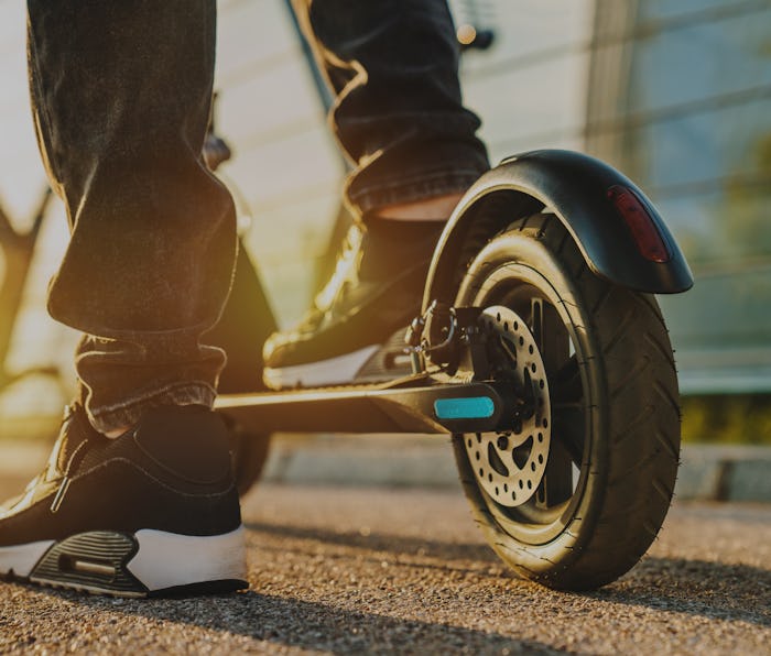 Close up of young man ready to discover the urban city at sunset with electric scooter or e-scooter