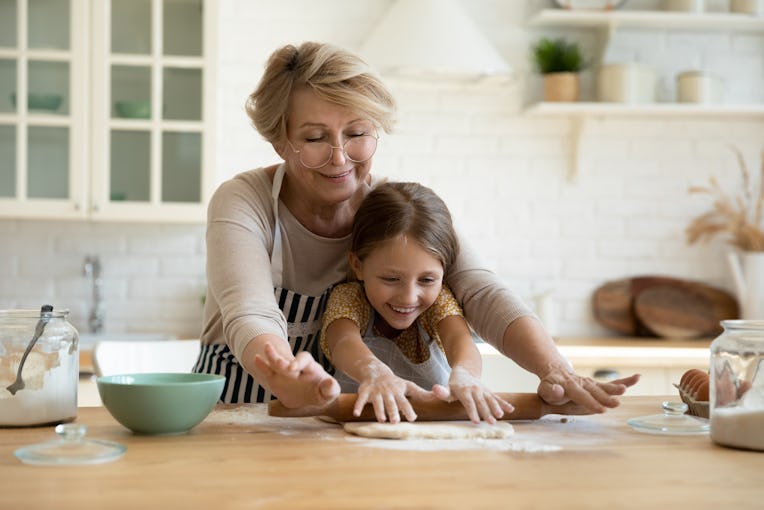 My little helper. Active aged grandma involve small grandkid girl in rolling yeast cookie dough with...