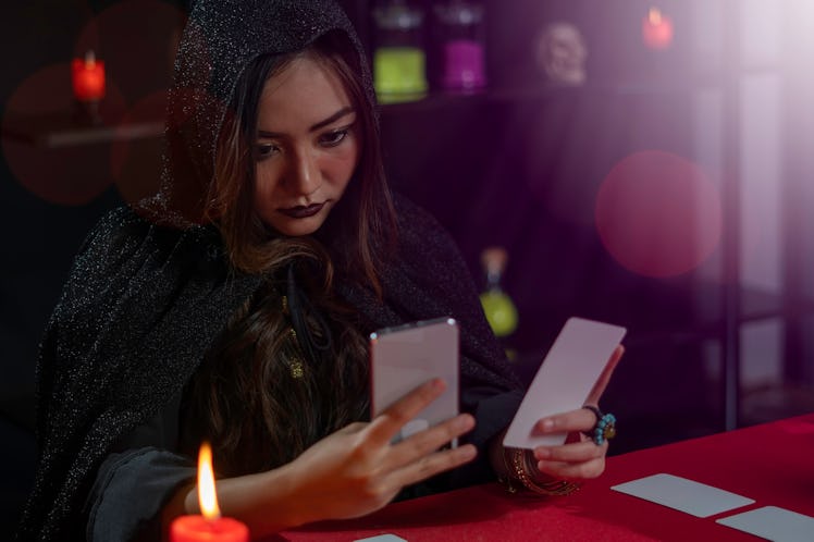 Female fortune teller reads tarot cards for predictions, telling customers by providing services via...