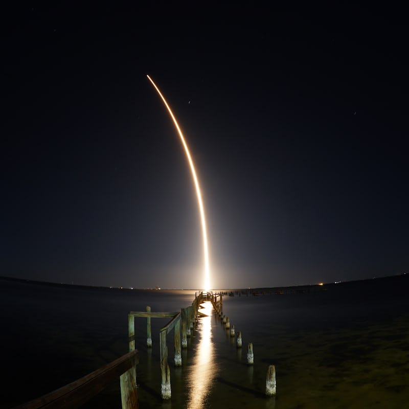 SpaceX rocket launch at night seen from Titusville, FL with destroyed dock in foreground