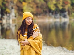 Young woman in yellow beanie standing in the forest during fall, affected by the October 2021 new mo...