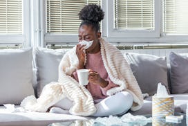 Sick day at home. African American woman has runny nose and common cold. Cough. Closeup Of Beautiful...