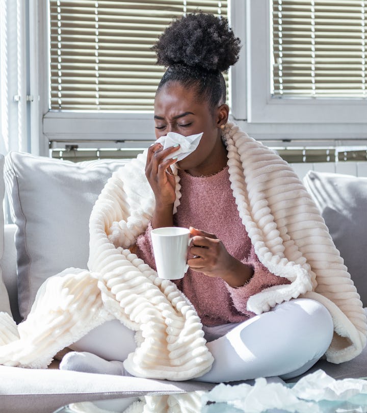 Sick day at home. African American woman has runny nose and common cold. Cough. Closeup Of Beautiful...